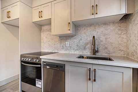 an updated kitchen with white cabinets and stainless steel appliances